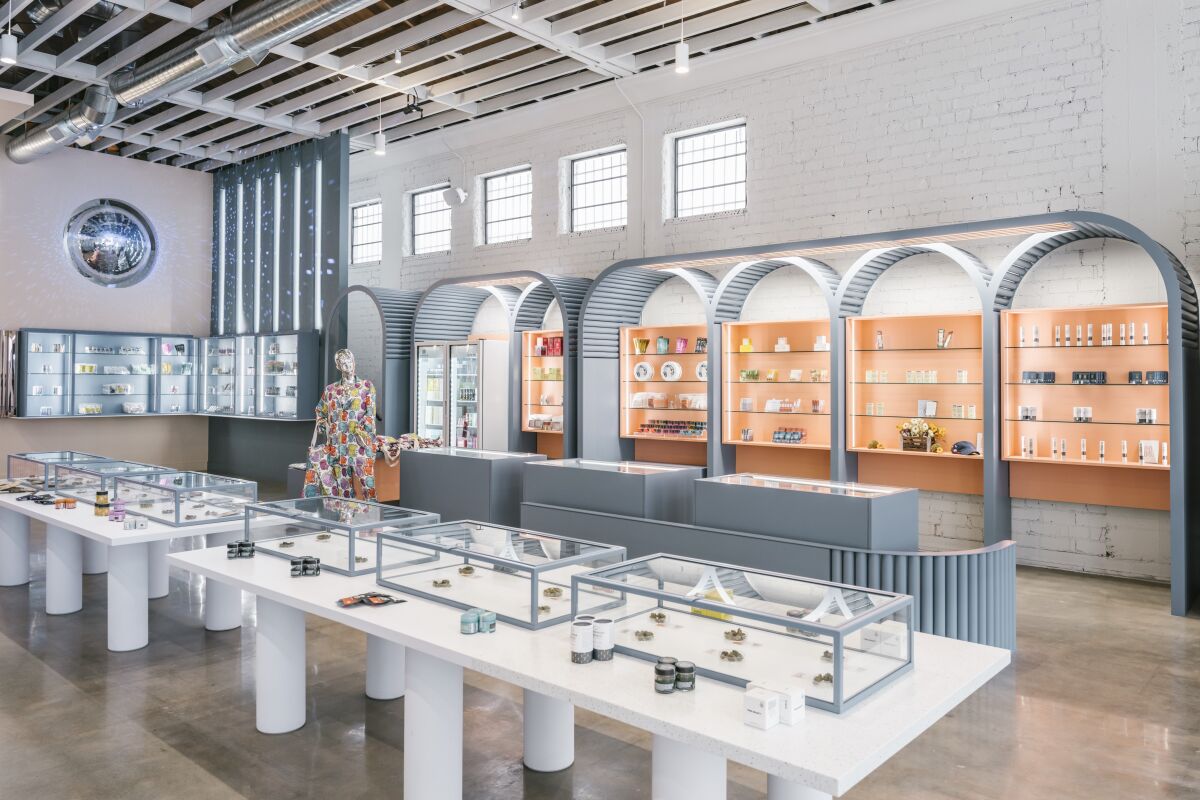 The interior of a brightly lit cannabis dispensary with glass cases and shelves filled with products.