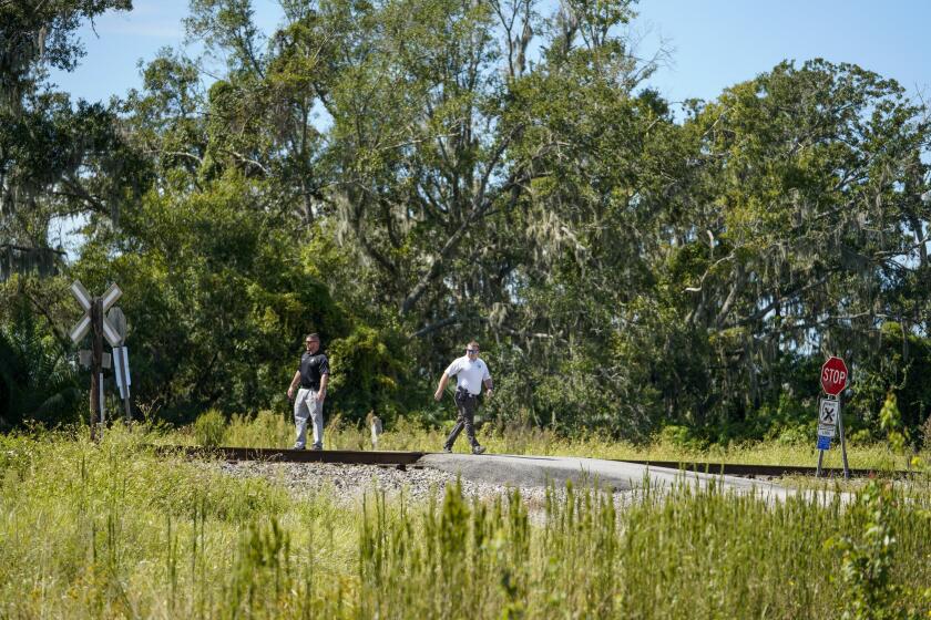 Law enforcement officials walk the site of a weekend fatal train collision, Monday, Sept. 25, 2023 in Plant City, Fla., that killed six people and left another in critical condition, when they were crossing the train tracks, on their way to a birthday party. The weekend crash between a train and a sports-utility vehicle that killed six people in Florida happened at a private road crossing where little more than a sign or two is required, no crossing gates, no flashing lights, no sound. (Martha Asencio-Rhine/Tampa Bay Times via AP)