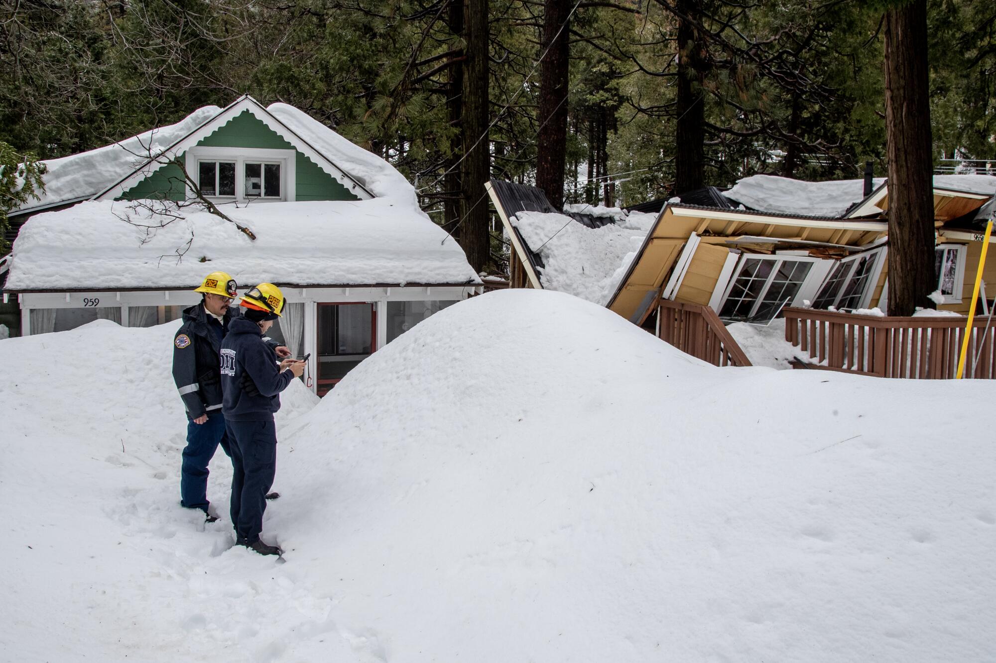 Firefighters stand near a snow covered building.
