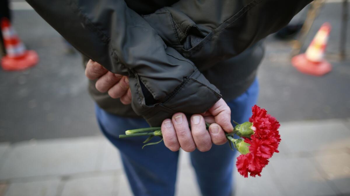 A man waits to leave a flower for the victims of a nightclub attack in Istanbul, Turkey.