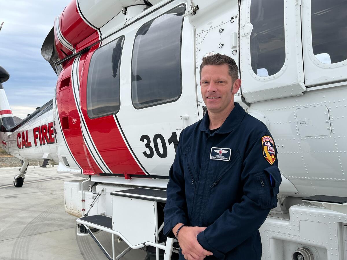 A pilot stand in front of his helicopter.