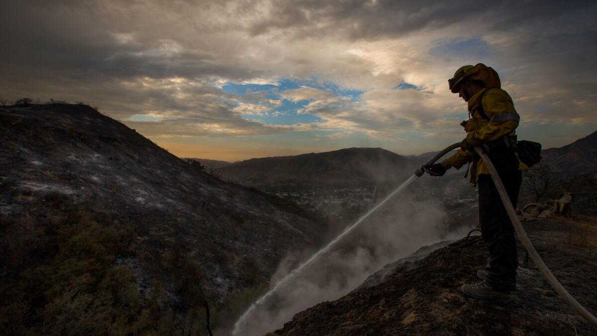 Los Angeles County firefighter Kevin Sleight extinguishes hot spots while battling the La Tuna fire.
