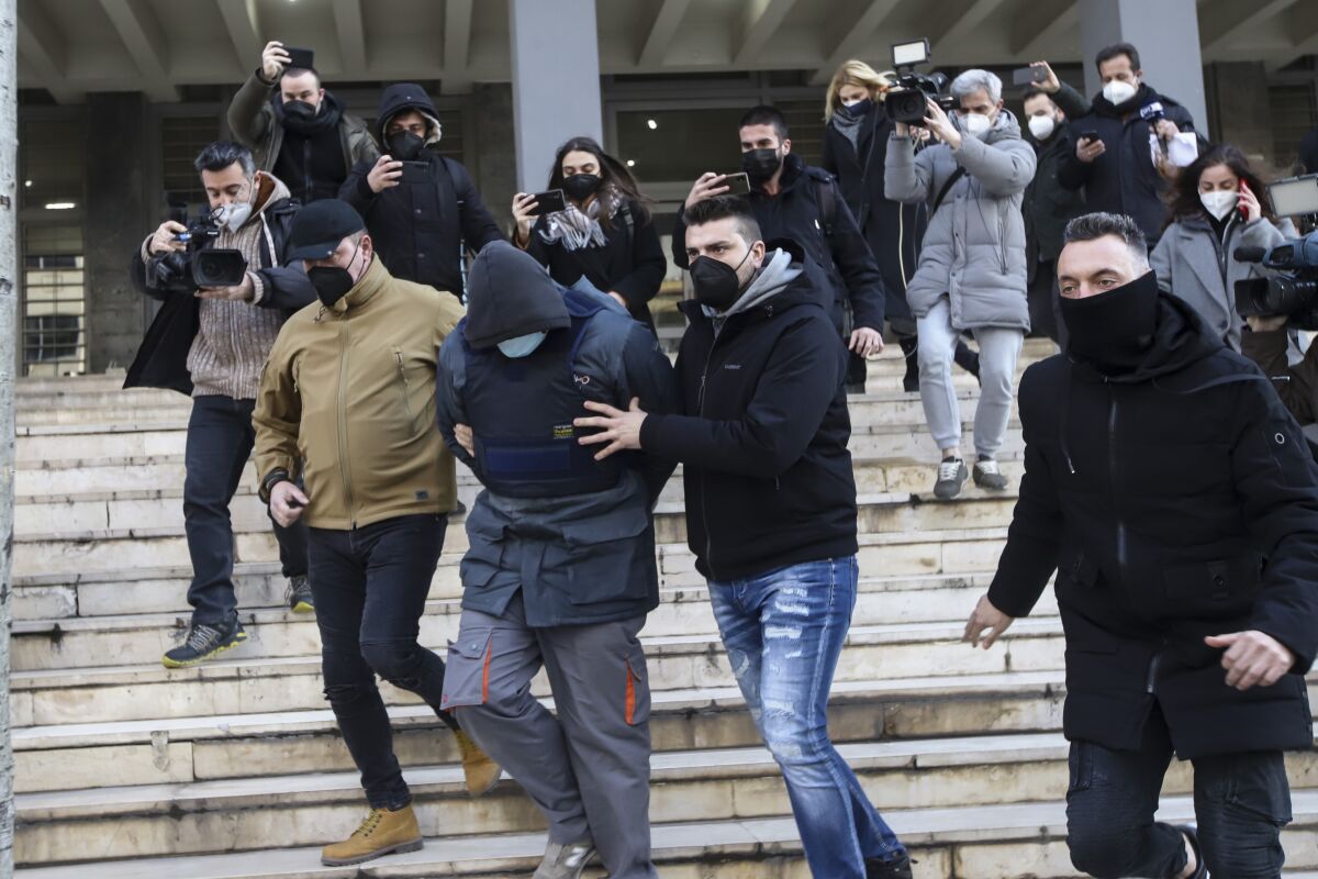 Greek police officers in plain clothes escort the 23 year-old man accused of the murder of 19-year-old city resident Alkis Kambanos as they leave the court house in Thessaloniki Greece, on Thursday Feb. 3, 2022. Police have raided multiple soccer supporters' clubs in the northern Greek city of Thessaloniki in the wake of attack that left a 19-year-old man dead that has been linked to violent fan rivalry. (MotionTeam/Eurokinissi via AP)