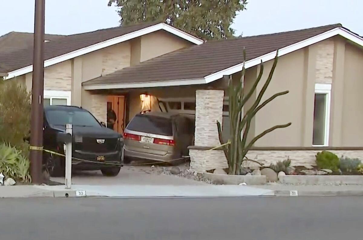 A car that has crashed into a home, with crime scene tape around the scene