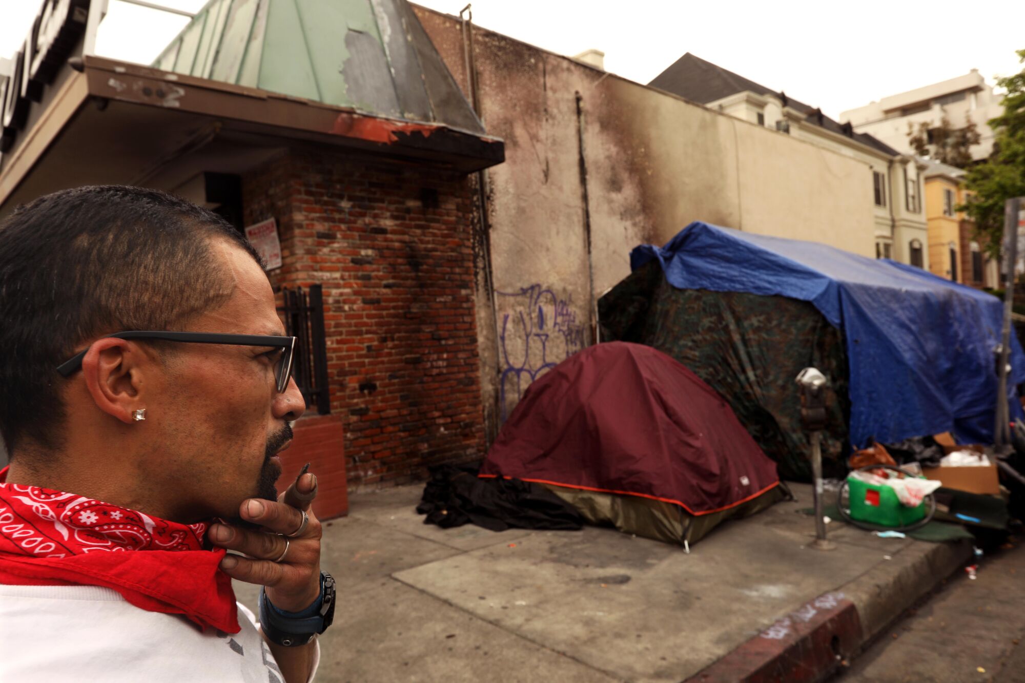 A man stands next to tents on the side of a building