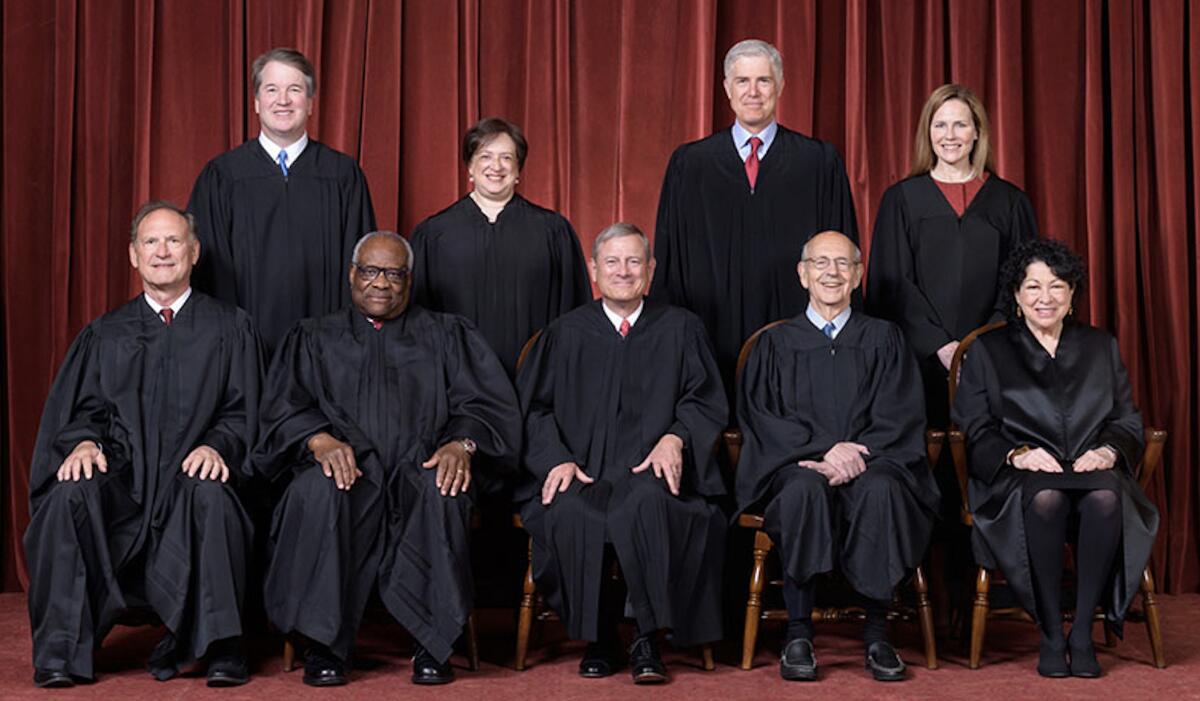 Supreme Court justices sit and stand for a portrait. 
