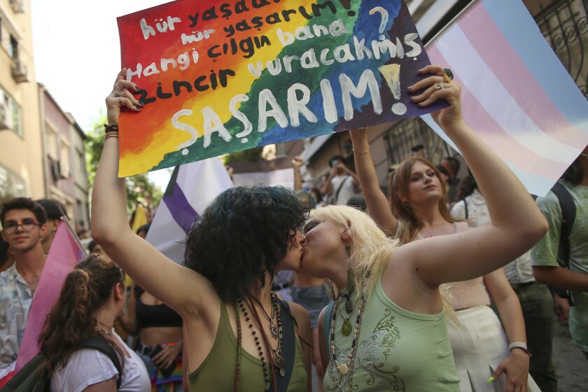 Two women kiss as they hold up a placard that reads in Turkish: "I live free. Who's the fool who will put me in chains? I would be shocked" during the LGBTQ Pride March in Istanbul, Turkey, Sunday, June 26, 2022. Dozens of people were detained in central Istanbul Sunday after city authorities banned a LGBTQ Pride March, organisers said. (AP Photo/Emrah Gurel)