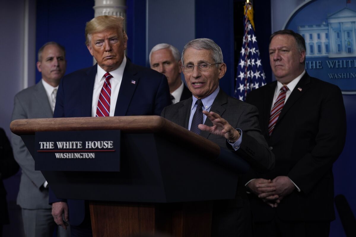 Dr. Anthony Fauci speaks surrounded by President Trump and others at the White House.