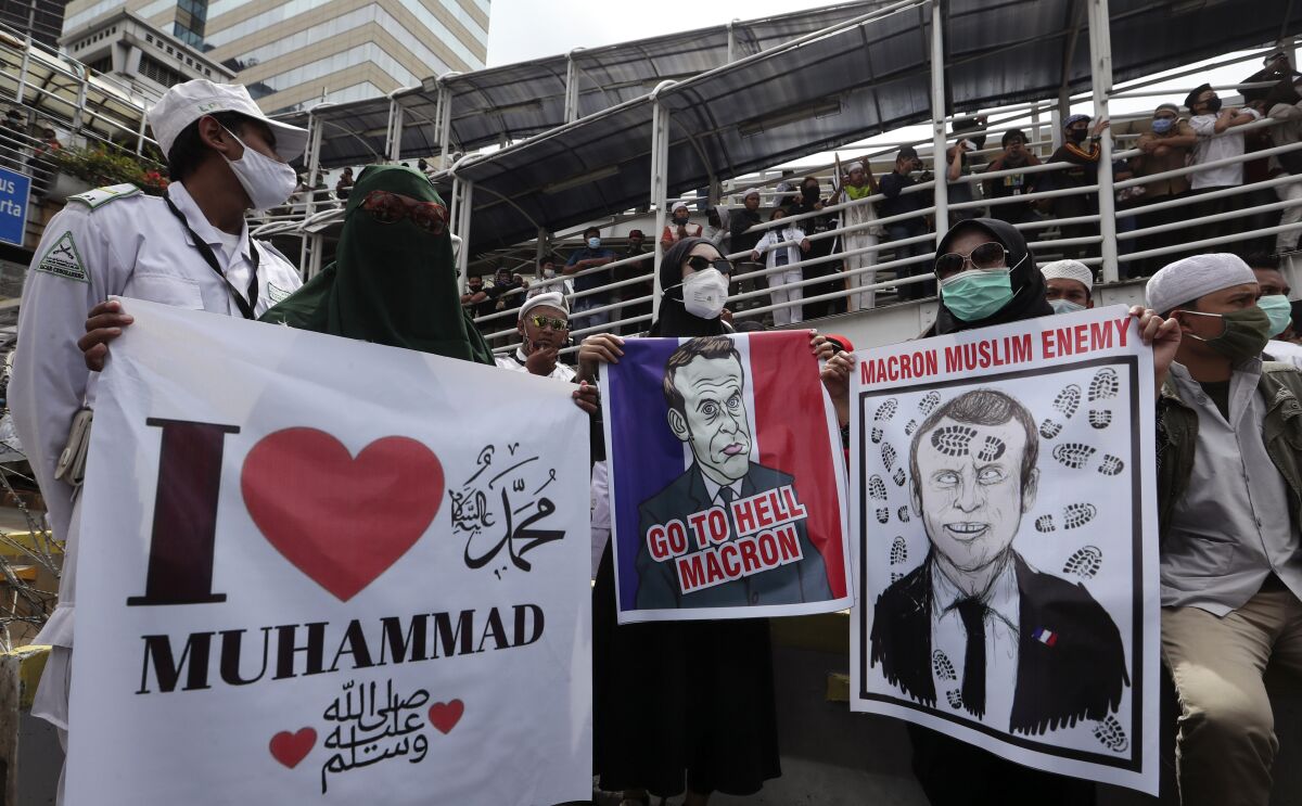 Indonesian Muslims protesters hold posters condemning French President Emmanuel Macron during an anti-France rally outside the France embassy in Jakarta, Indonesia, Monday, Nov. 2, 2020. Indonesian Muslims marched to the heavily guarded France Embassy in Indonesia's capital on Monday to protest France's president and his staunch support of secular laws that deem caricatures depicting the Prophet Muhammad as protected speech.(AP Photo/Achmad Ibrahim)