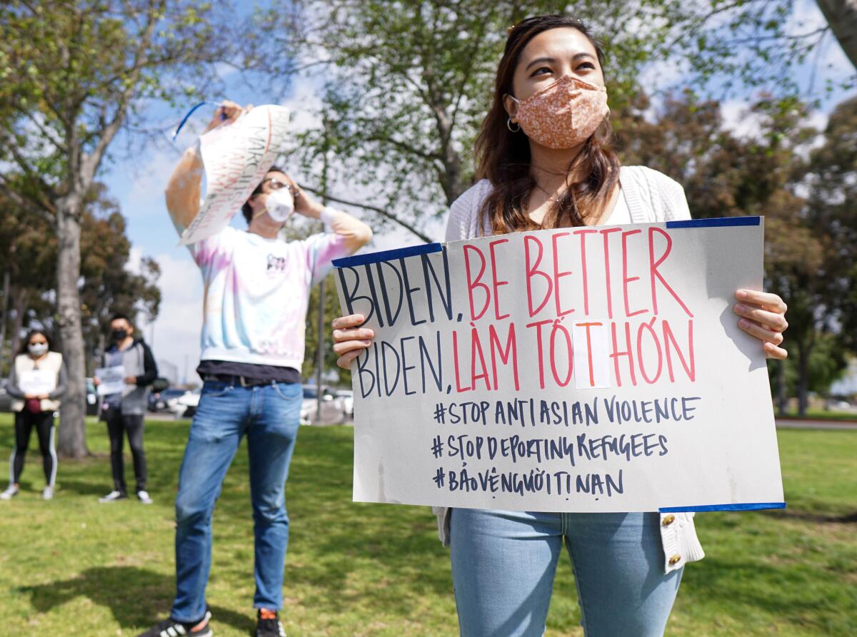 Protesters with face masks hold signs at a rally. 