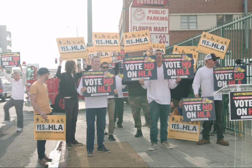 People stand on a sidewalk holding signs for and against ballot measure HLA.