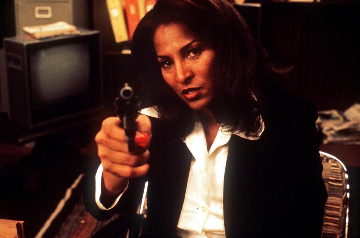 A woman in a blazer points a gun.