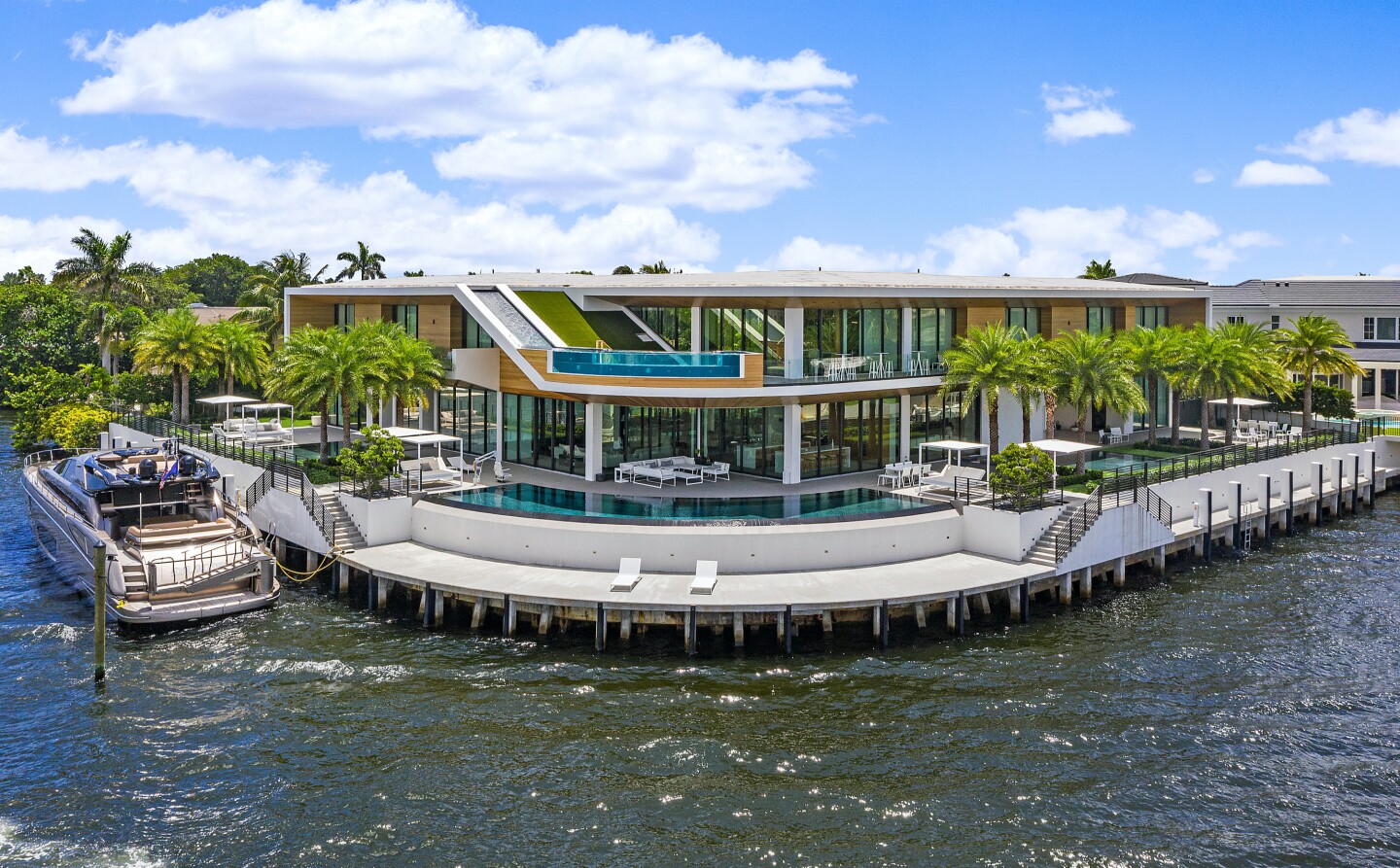 Built in 2019, the wood-and-glass mansion includes 343 feet of water frontage and four infinity pools, including one fed by a waterfall from the roof.