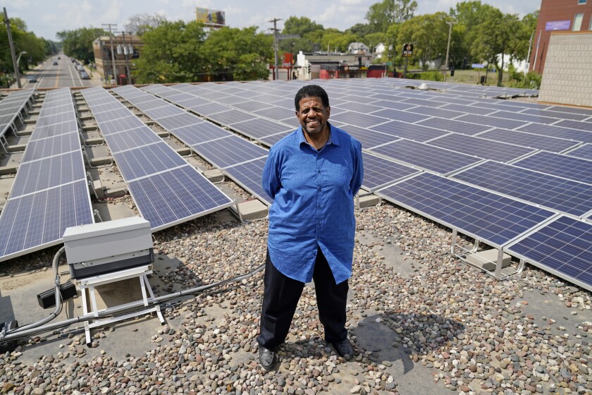 Bishop Richard Howell poses Aug. 19, 2021 beside some of the 630 solar panels on the roof of Shiloh Temple International Ministries in Minneapolis The church is one of many "community solar" providers popping up around the U.S. as surging demand for renewable energy inspires new approaches. Aug. 19, 2021, in Minneapolis. (AP Photo/Jim Mone)