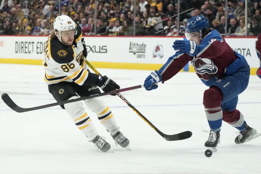 Boston Bruins right wing David Pastrnak, left, fires a shot past Colorado Avalanche defenseman Samuel Girard in the second period of an NHL hockey game, Wednesday, Dec. 7, 2022, in Denver. (AP Photo/David Zalubowski)