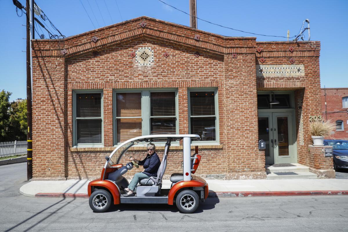 Julie Stolnack, a fourth-generation resident who uses an electric cart to get around El Segundo, is shown outside a century-old building that was formerly the police station.