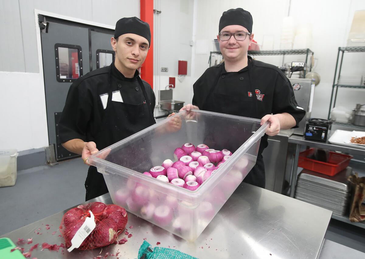 Students Matt Plonski and Lukas Romero, from left, clean dozens of red onions at Bracken's Kitchen in Garden Grove.