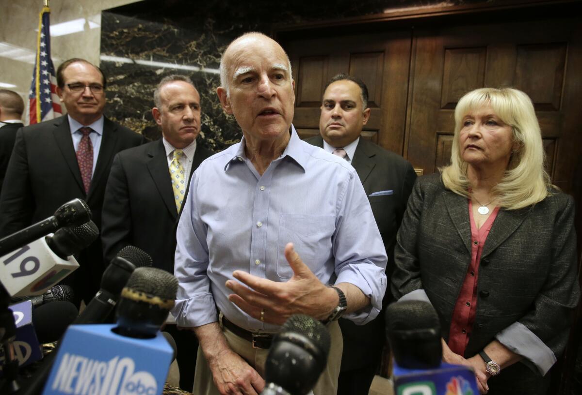 Gov. Jerry Brown, center, responds to a question concerning the compromise plan reached on reducing the state's prison population, during a Capitol news conference in Sacramento.