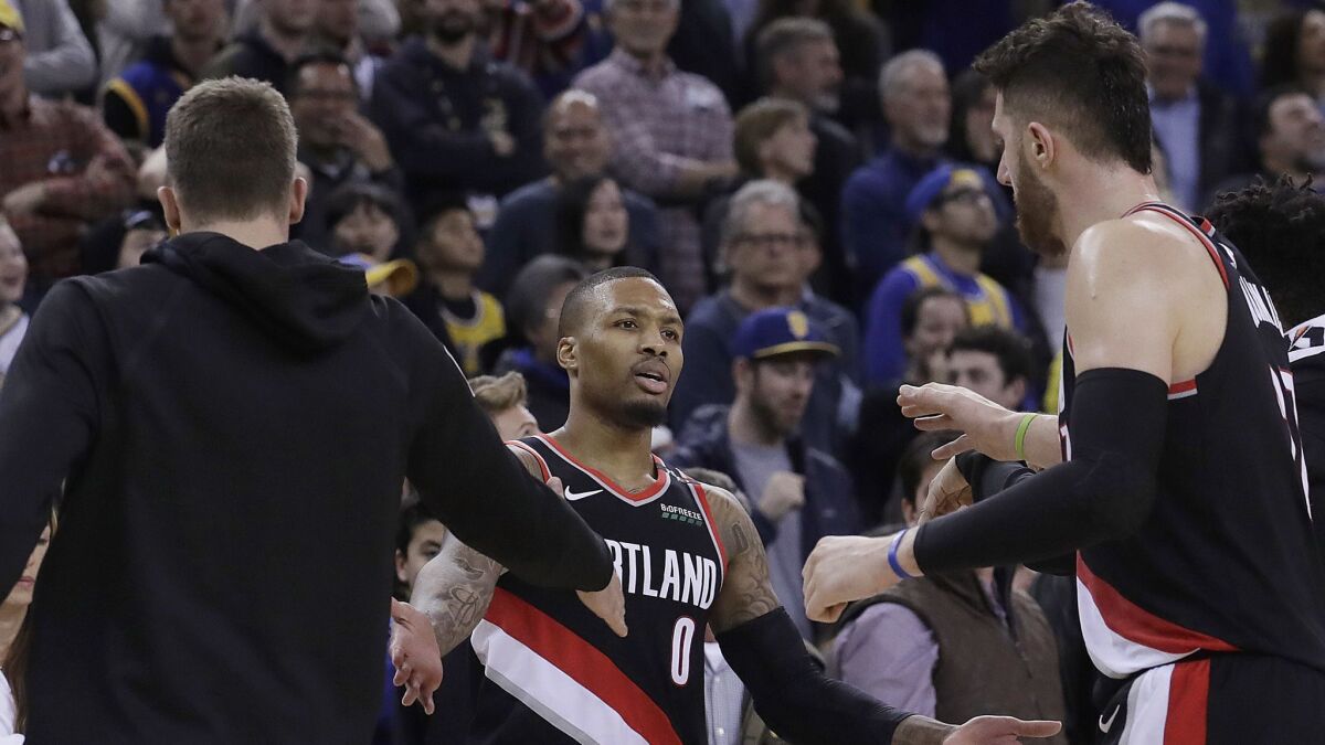Portland Trail Blazers guard Damian Lillard, center, celebrates with teammates after scoring a three-point basket against the Golden State Warriors during overtime.