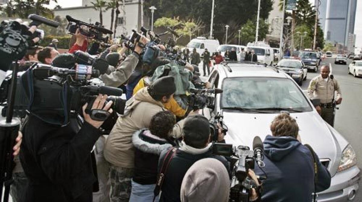 Media and paparazzi swarm a car hoping for a shot of Britney Spears. She was not inside, but such image-seeking packs have prompted a councilman to call for a zone of clear space in public areas.
