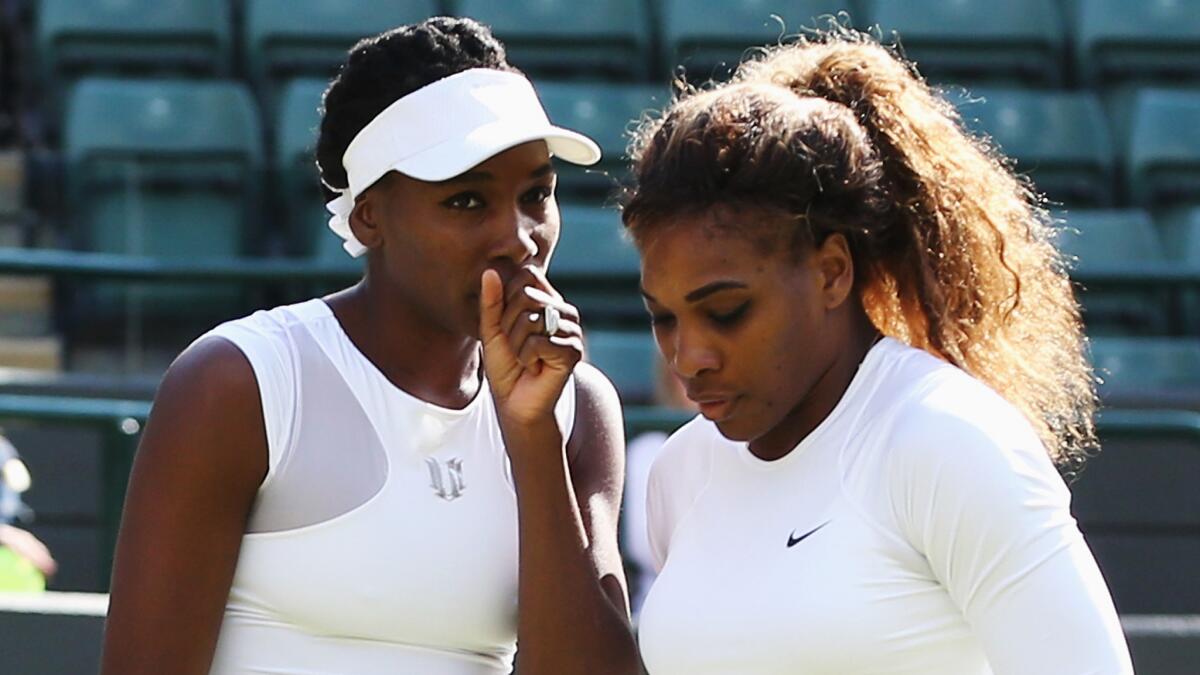 Venus, left, and Serena Williams look on during their doubles match at Wimbledon on Tuesday. Serena Williams defaulted out of the match when she couldn't hit a serve fast enough to register on the speed gun.