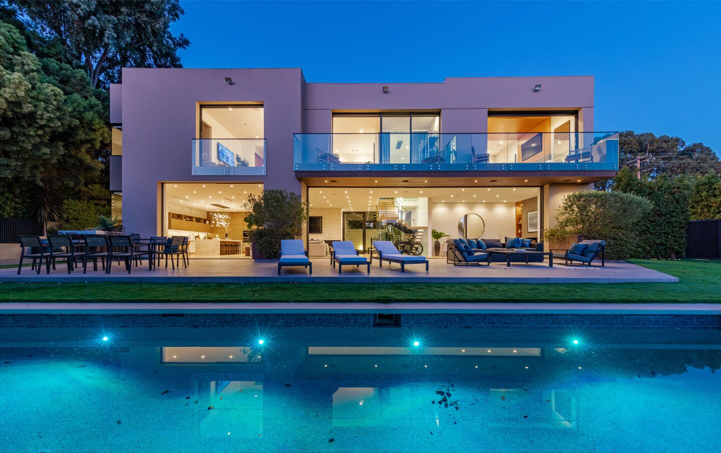 The pool is in front of the furnished patio and house.