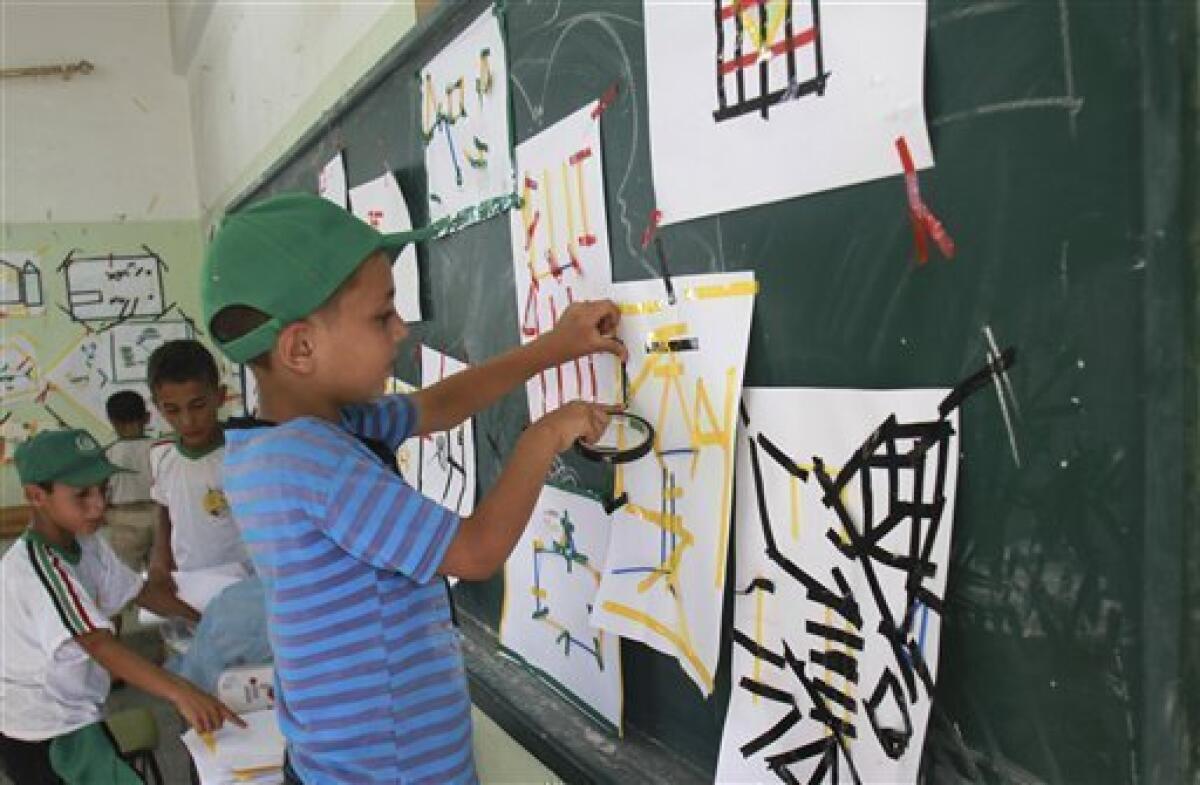 In this Wednesday, July 11, 2012 photo, Palestinian boys make drawings at a summer camp run by Hamas inside a school in Al-Qarara near Khan Younis, southern Gaza Strip. Since taking over Gaza five years ago, Hamas has competed with a U.N. agency for the hearts of Palestinian children. Each side ran summer camps, with Hamas featuring lessons in Islam and political indoctrination and the U.N. offering sports and games. Hamas has now won by default _ the U.N. canceled its camps this year because of a drop in donations.(AP Photo/Adel Hana)