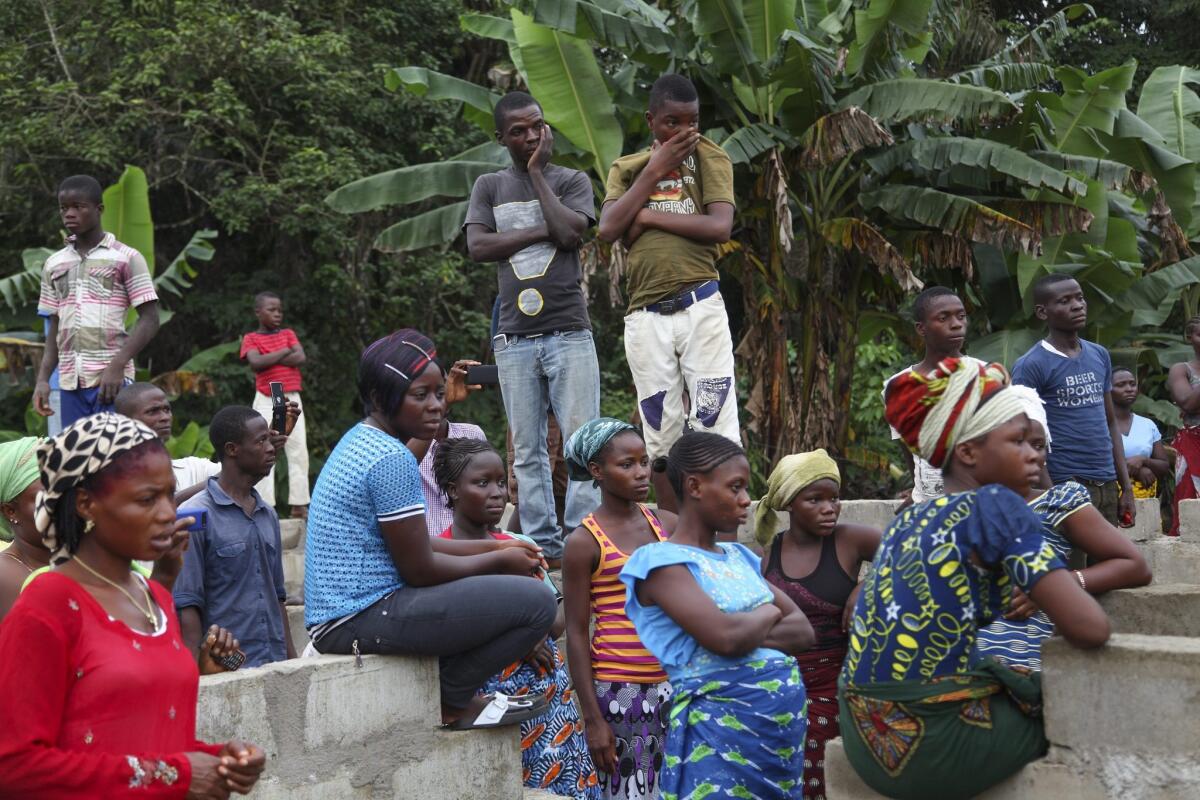 Liberian relatives of Ebola victims and members of the community react as bodies are taken away for burial in Liberia.