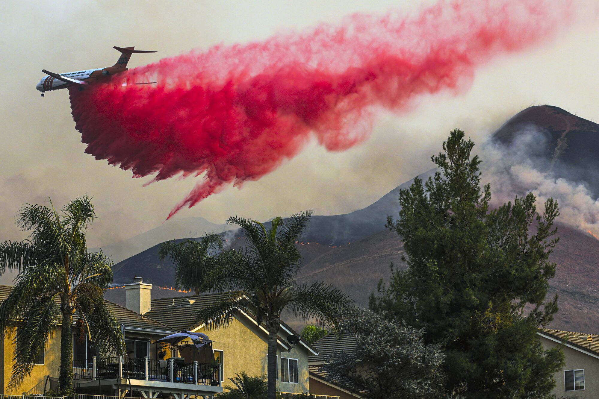 An air tanker fighting the Blue Ridge fire makes a fire retardant drop Tuesday behind homes in Chino Hills.