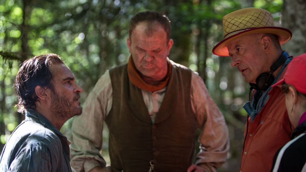Joaquin Phoenix, from left, and John C. Reilly work with director Jacques Audiard on the set of "The Sisters Brothers."