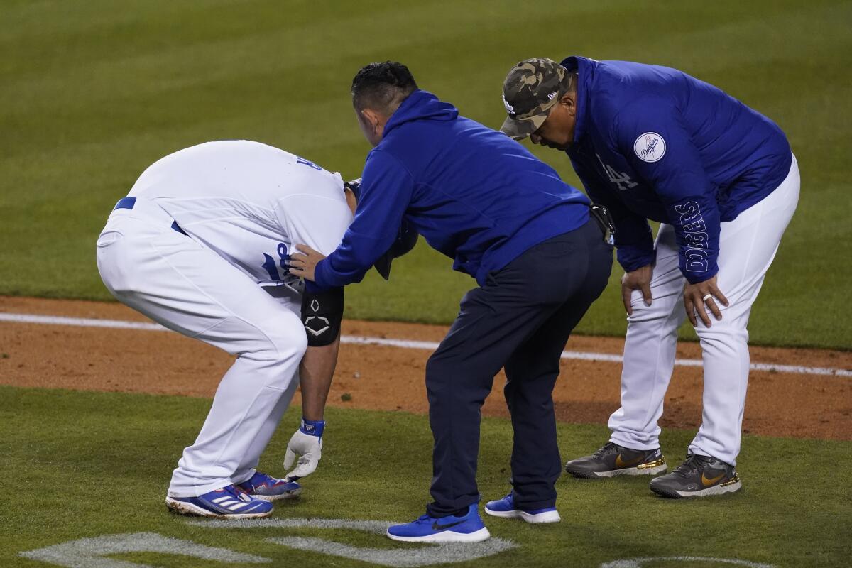 Dodgers shortstop Corey Seager is attended to by a team trainer while talking to manager Dave Roberts.