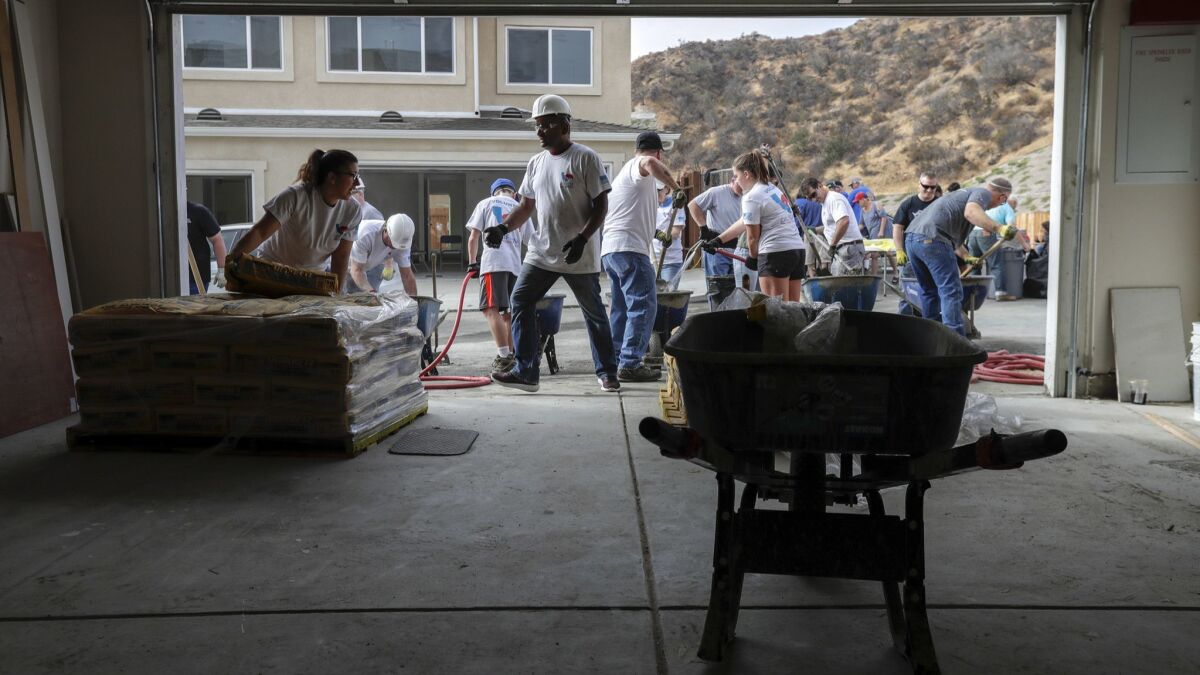 Volunteers work outside the home that is being purchased by Iraq war veterans Marlon and Josette Tolentino at the Homes 4 Families development in Santa Clarita.