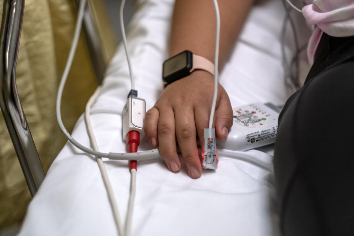 A 12-year-old patient's finger is attached to a pulse monitor in a hospital. 