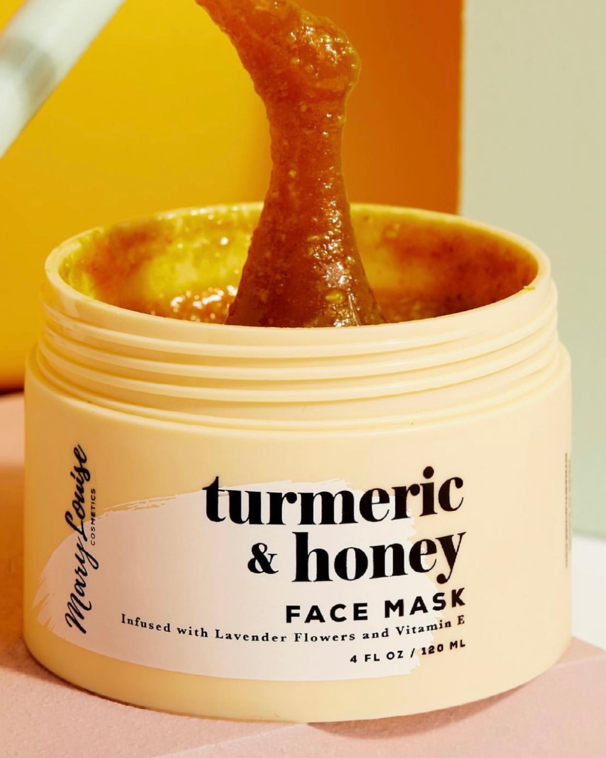 a closeup of product being lifted out of a light yellow Mary Louise Cosmetics turmeric & honey face mask jar