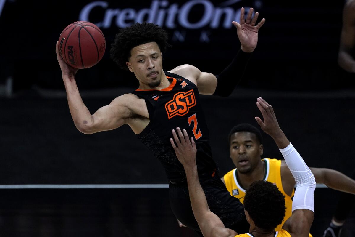 Oklahoma State's Cade Cunningham (2) passes over Baylor's MaCio Teague during the first half of an NCAA college basketball game in the semifinals of the Big 12 tournament in Kansas City, Mo., Friday, March 12, 2021. (AP Photo/Charlie Riedel)