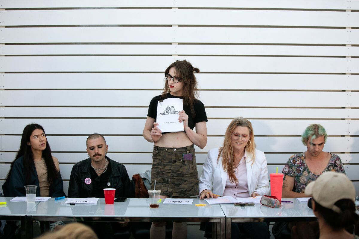 A person shows a script to others sitting at a table.