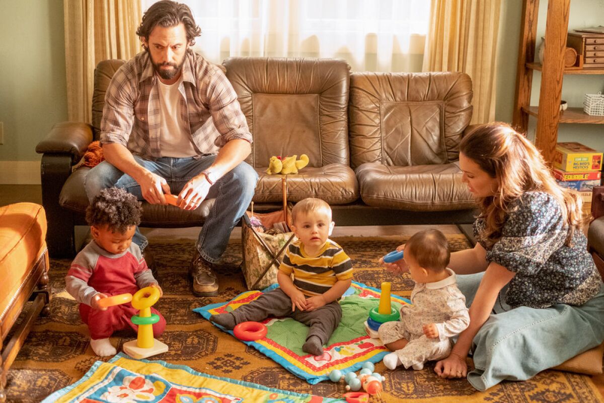 Two parents with their three infant children in a living room