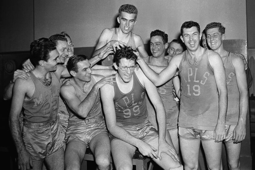 George Mikan (No. 99, wearing glasses), Minneapolis center, gets his hair mussed by teammates.