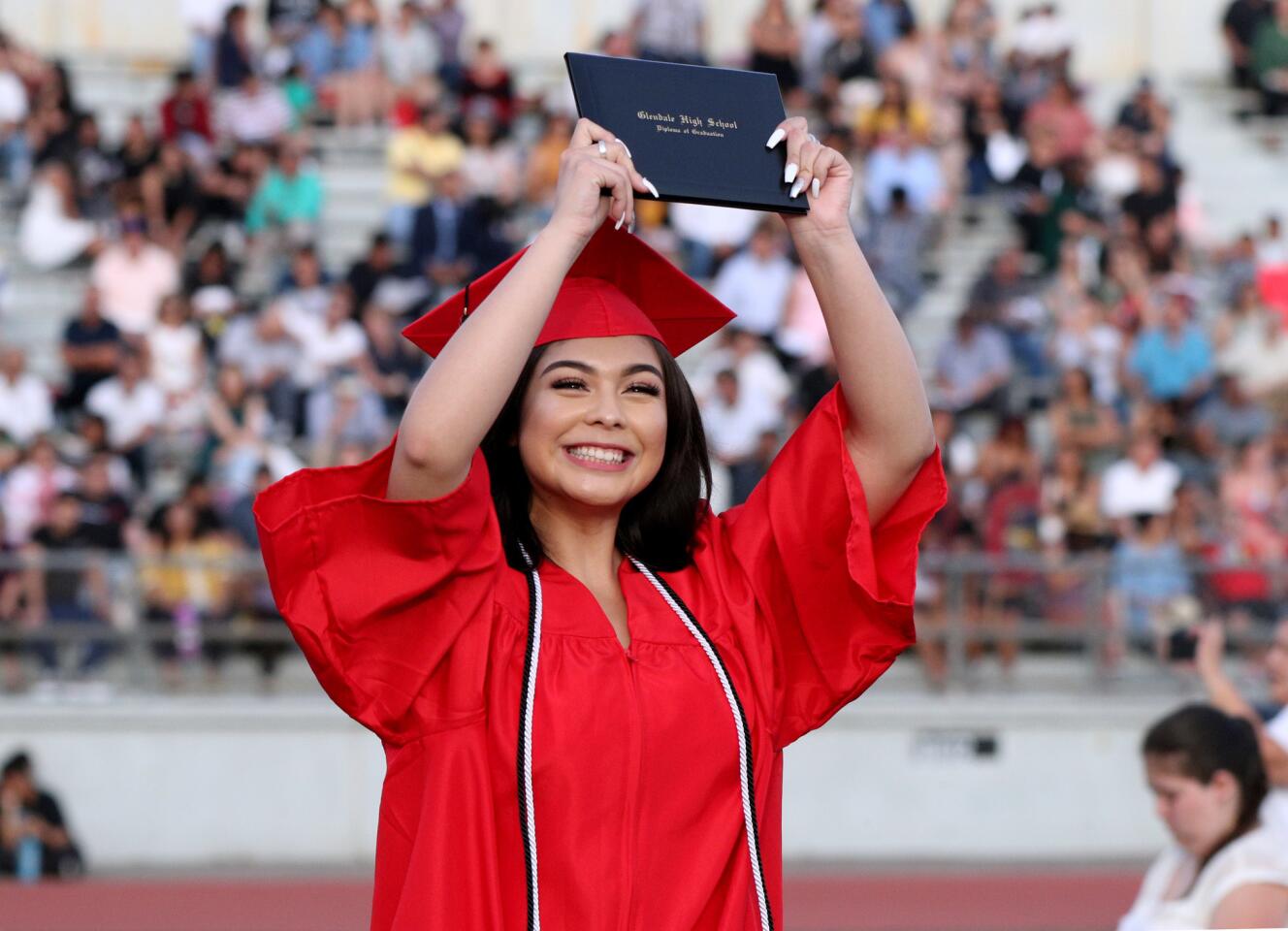 Glendale High School graduate Bianca Gonzalez shows off her diploma as she walks back to her seat during the commencement ceremony for the class of 2019, at Moyse Field in Glendale on Tuesday, June 11, 2019.