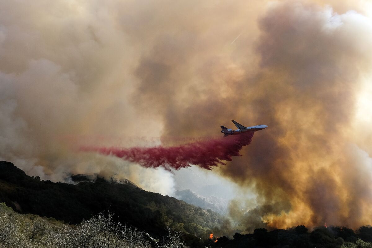 FILE - In this Oct. 13, 2021, file photo, an air tanker drops retardant on a wildfire in Goleta, Calif. Firefighters persisted in making progress Saturday, Oct. 17, against a wildfire burning for a sixth day in Southern California coastal mountains. The Alisal Fire in the Santa Ynez Mountains west of Santa Barbara grew only slightly since Friday to nearly 27 square miles (69 square kilometers). It was 50% contained. (AP Photo/Ringo H.W. Chiu, File)