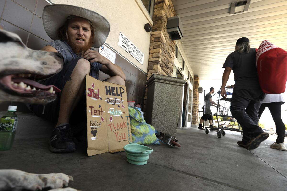 Anthony Wainscott, 33, and his dog, Roscoe, sit in 107-degree heat in Palmdale on Sunday.