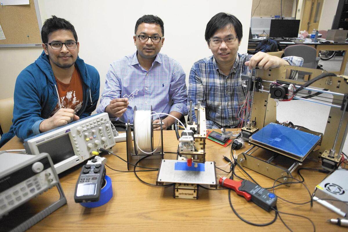 Mohammad Al Faruque, center, director of UC Irvine’s Advanced Integrated Cyber-Physical Systems Lab, poses in March with graduate students Sujit Rokka Chhetri, left, and Jiang Wan as they discuss their research of how a 3-D printer’s noise emissions can reveal sensitive information.