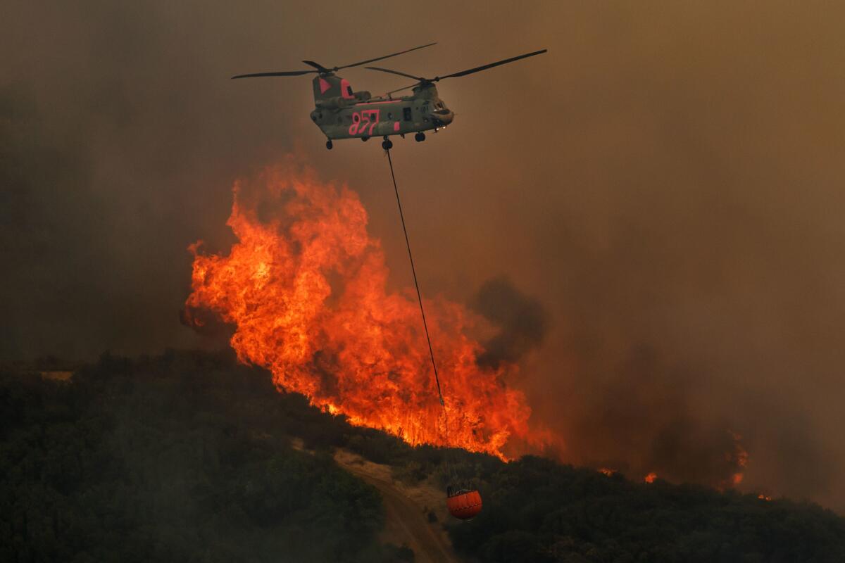 A helicopter prepares to make a water drop near the raging River fire west of Lakeport, Calif.