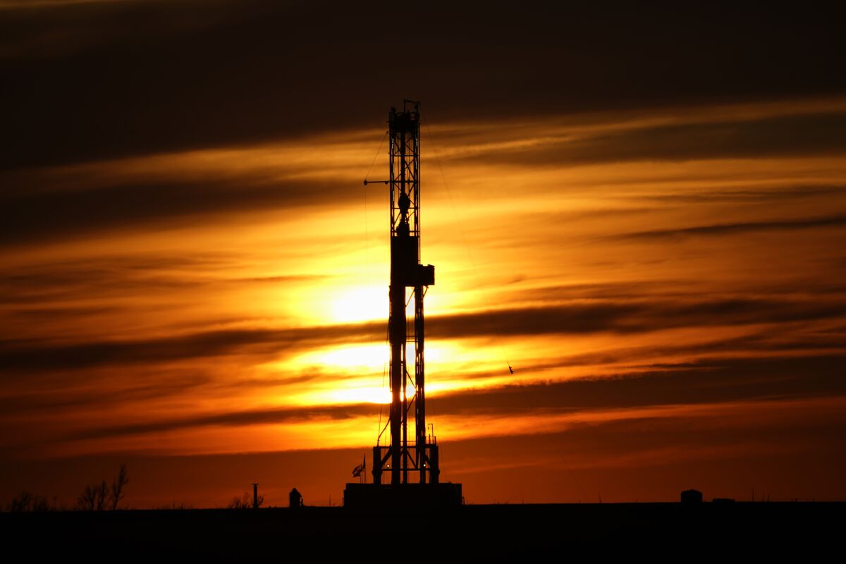 FILE - An oil drilling rig is pictured at sunset, March 7, 2022, in El Reno, Okla. Social media users are suggesting soaring fuel prices in the U.S. are part of a government scheme to get drivers into electric vehicles. The conspiracy theory posts are spreading across Facebook, Twitter and Instagram. (AP Photo/Sue Ogrocki, File)