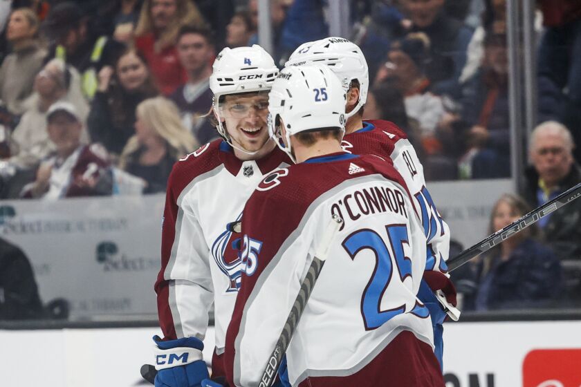 Colorado Avalanche defenseman Bowen Byram, left, celebrates after his goal with forwards Logan O'Connor, front, and Darren Helm during the first period of an NHL hockey game against the Anaheim Ducks in Anaheim, Calif., Monday, March 27, 2023. (AP Photo/Ringo H.W. Chiu)