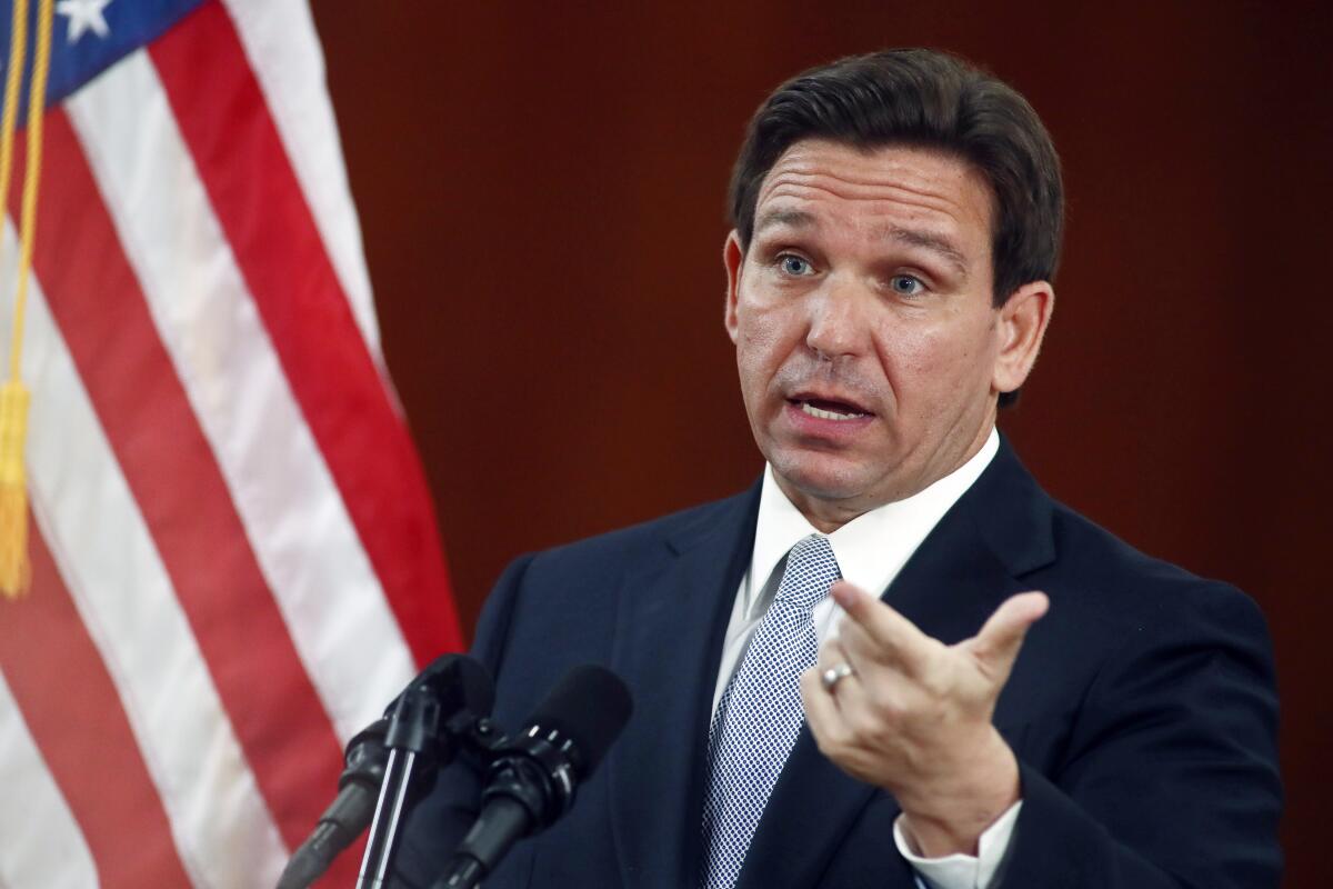 Florida Gov. Ron DeSantis raises his eyebrows and gestures as he speaks into a microphone. 