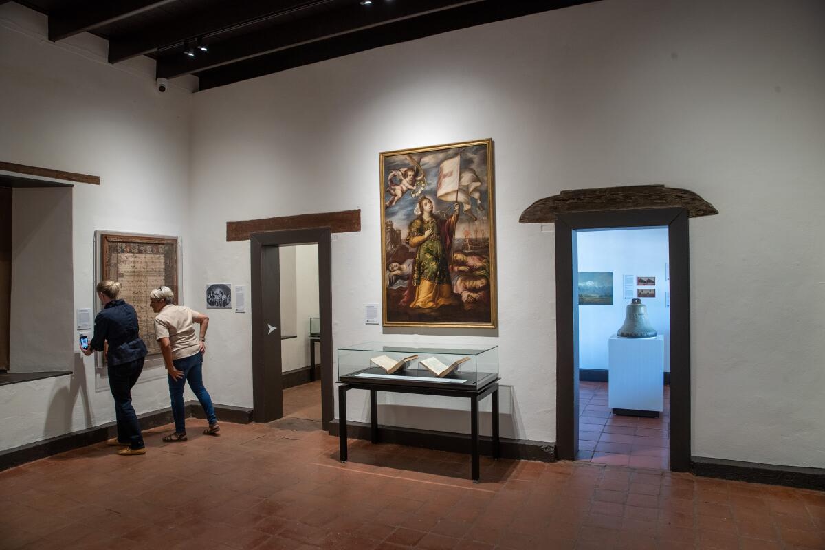 Two people visit a gallery inside the Mission San Gabriel Museum.
