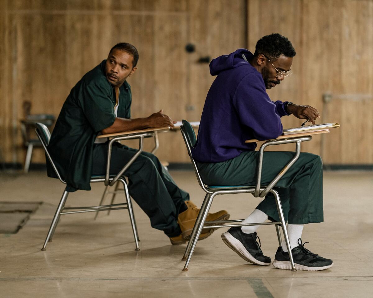 Two men in prison sit in a class.