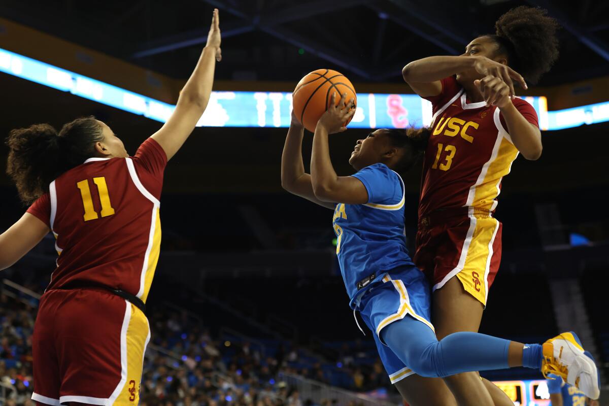 UCLA guard Londynn Jones leans into a shot between the defense of USC's Rayah Marshall (13) and Destiny Littleton (11).