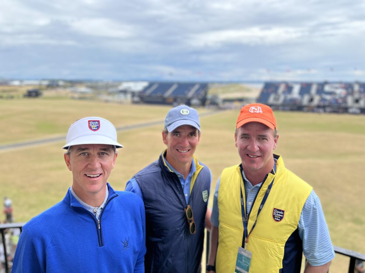 Cooper, Eli and Peyton Manning stand on a balcony of the hotel they bought.